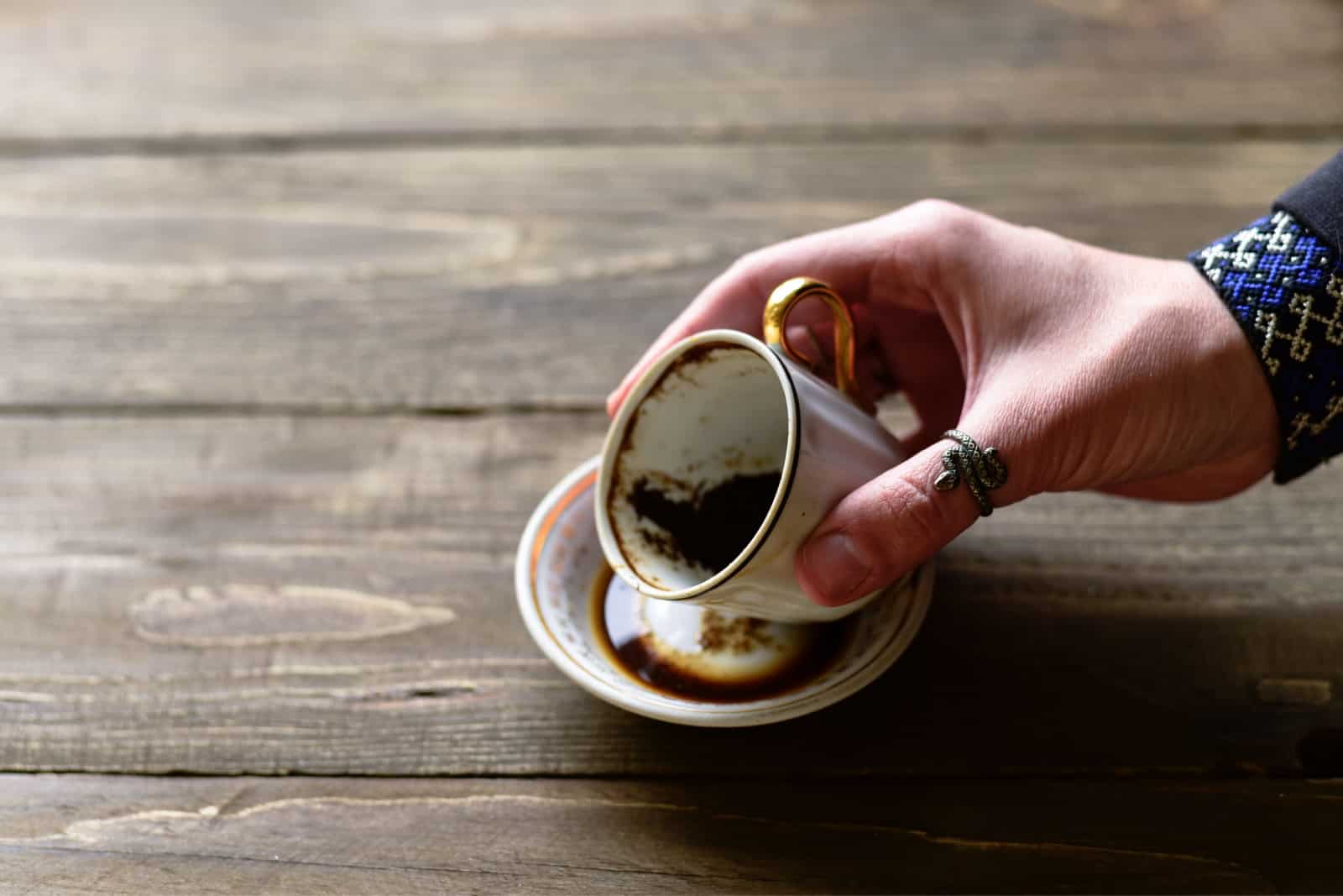 Main de diseuse de bonne aventure femme avec une tasse de marc de café