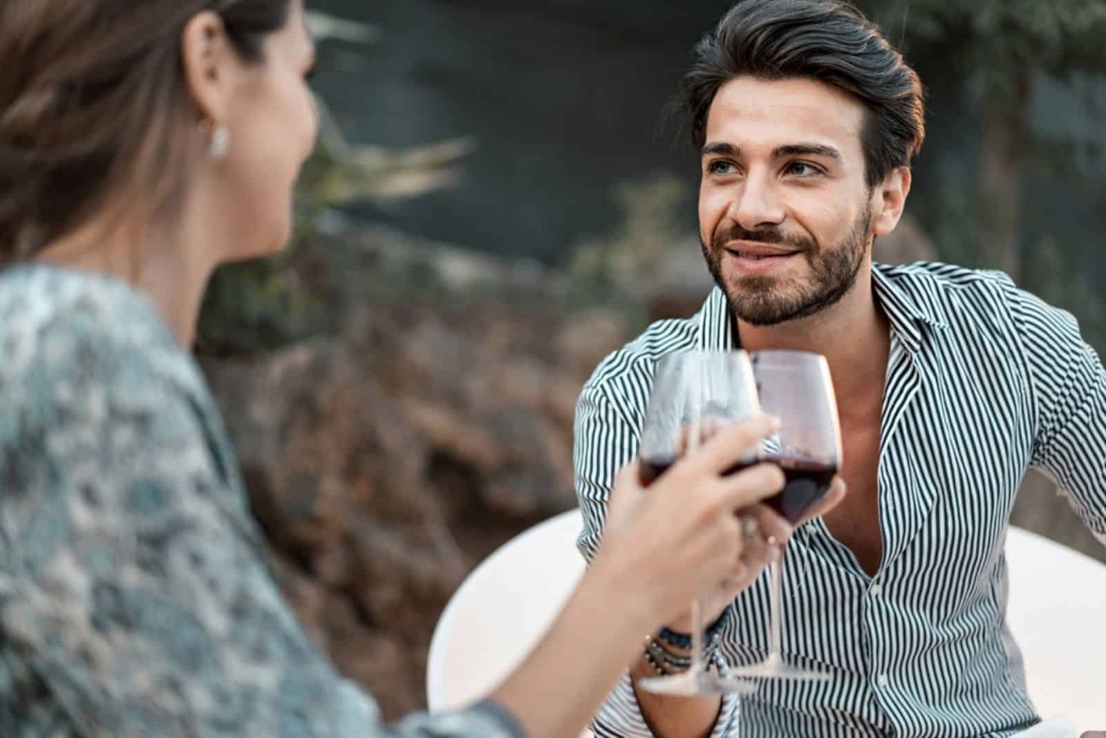 un homme et une femme sont assis à une table et boivent du vin