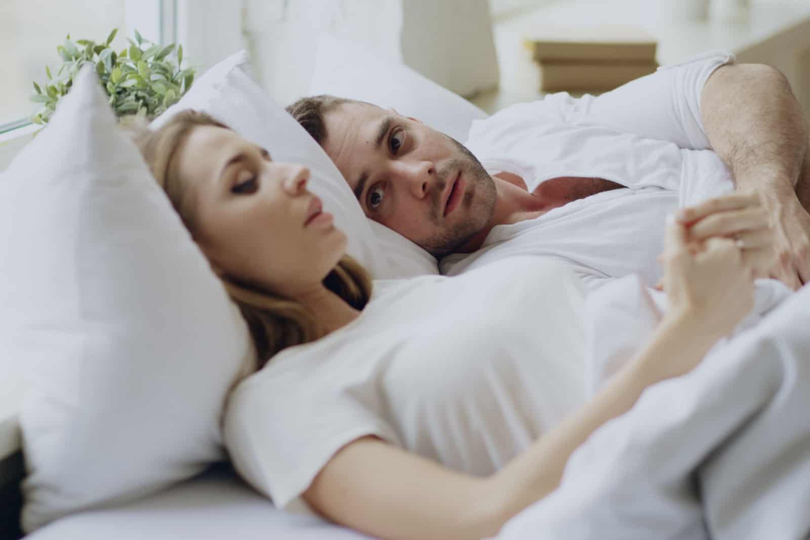 couple avec des problèmes relationnels ayant une conversation émotionnelle en position couchée dans son lit à la maison