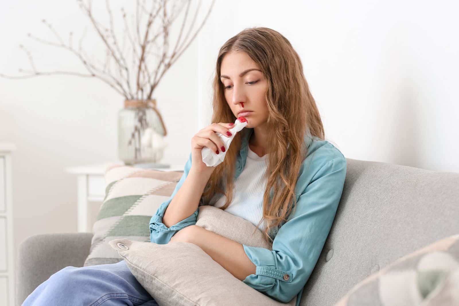 femme déprimée assise sur un canapé avec saignement de nez
