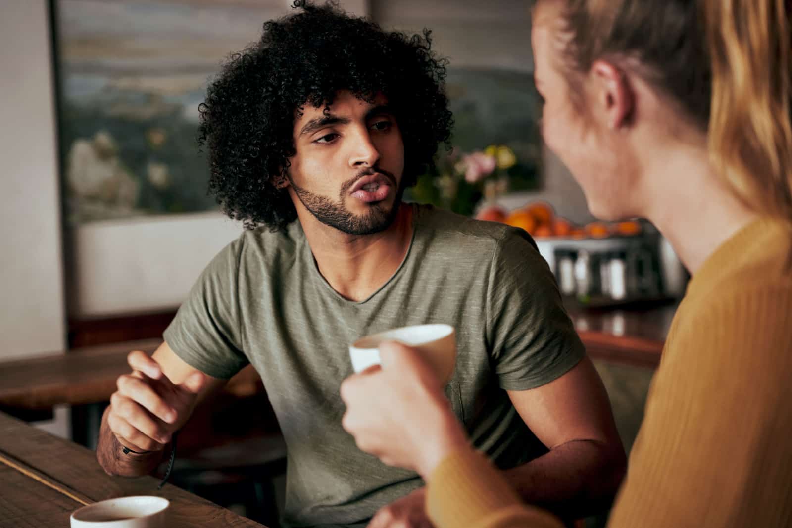 homme avec un afro en conversation sérieuse avec une femme assise dans un café