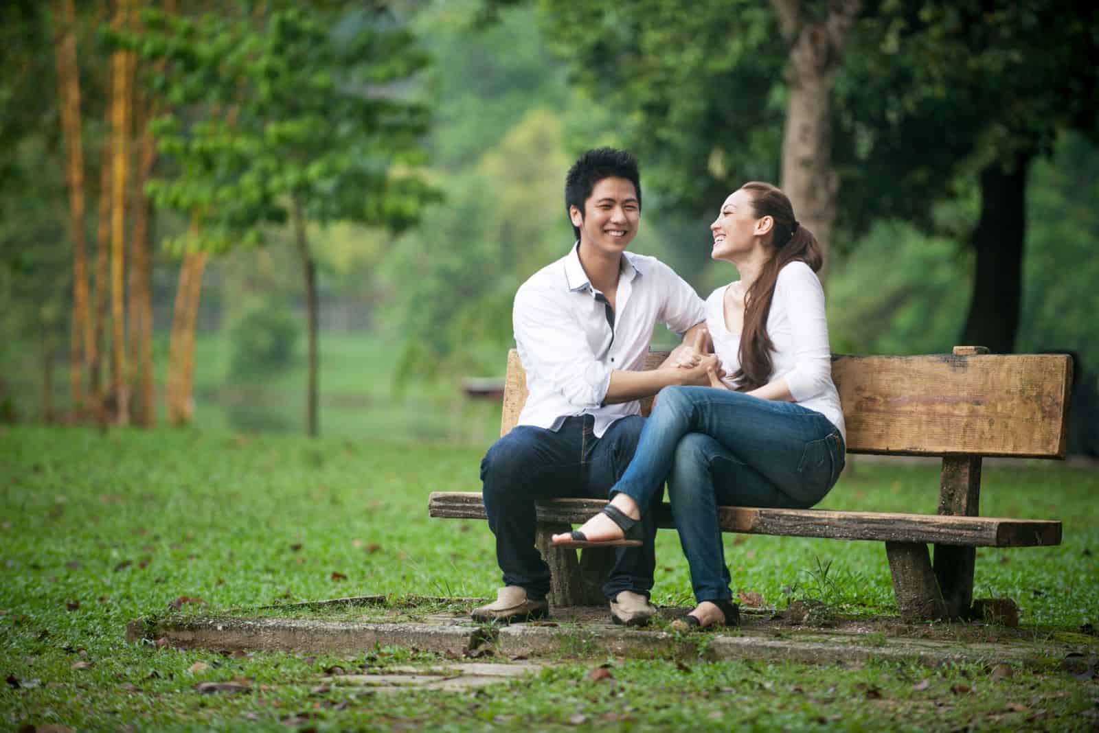 homme et femme souriants assis sur un banc de parc