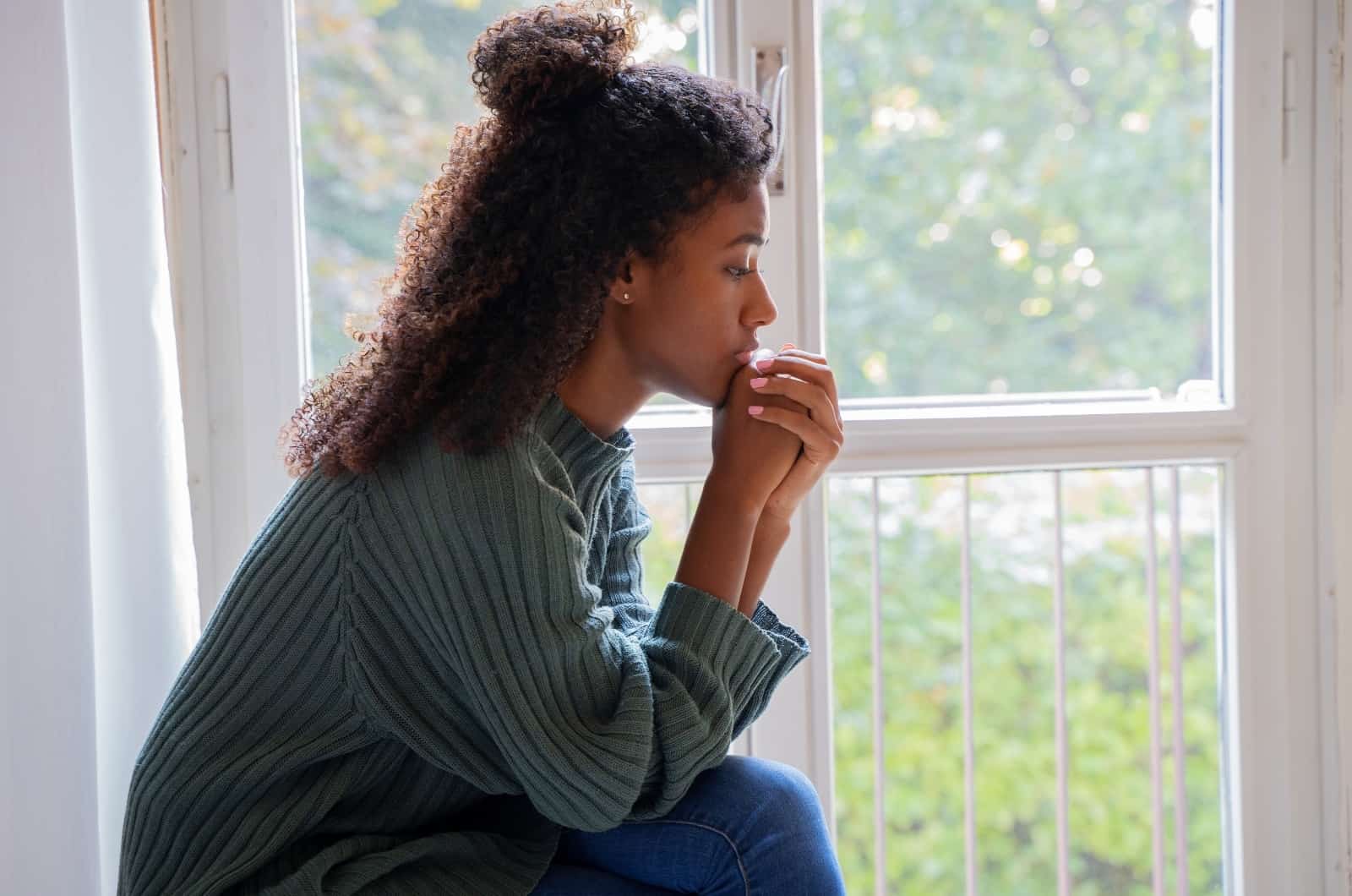 jeune femme priant devant la fenêtre