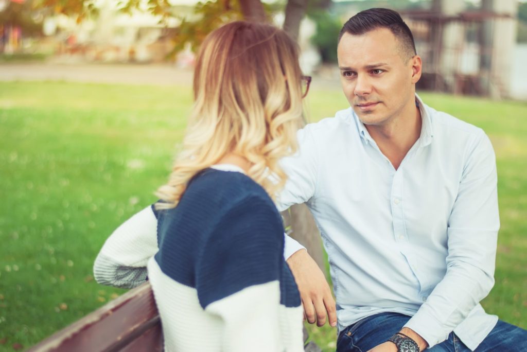un couple amoureux est assis sur un banc de parc et parle