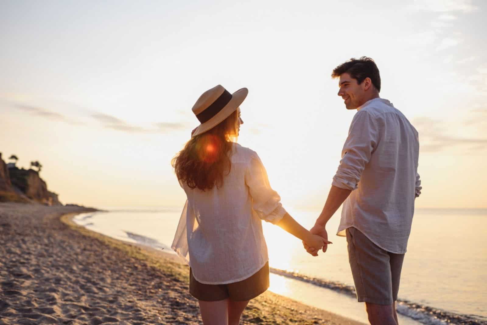 un homme et une femme souriants marchent sur la plage