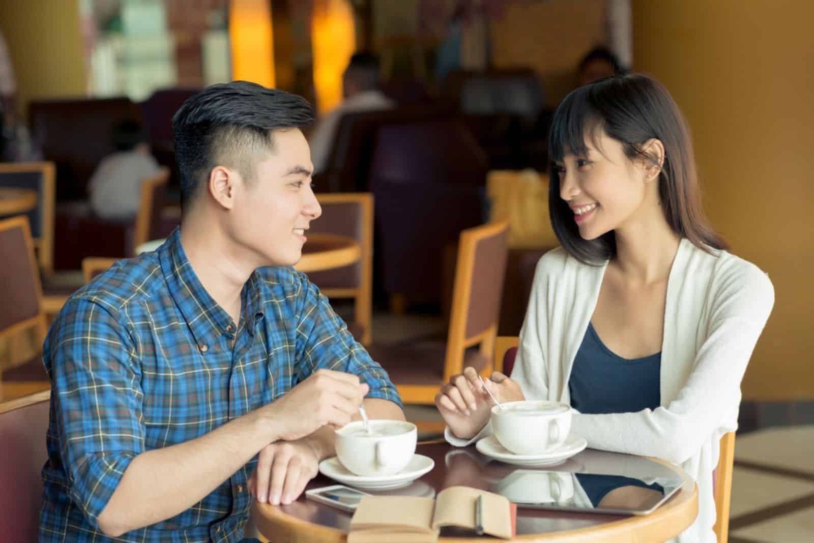 un jeune couple est assis dans un café et parle