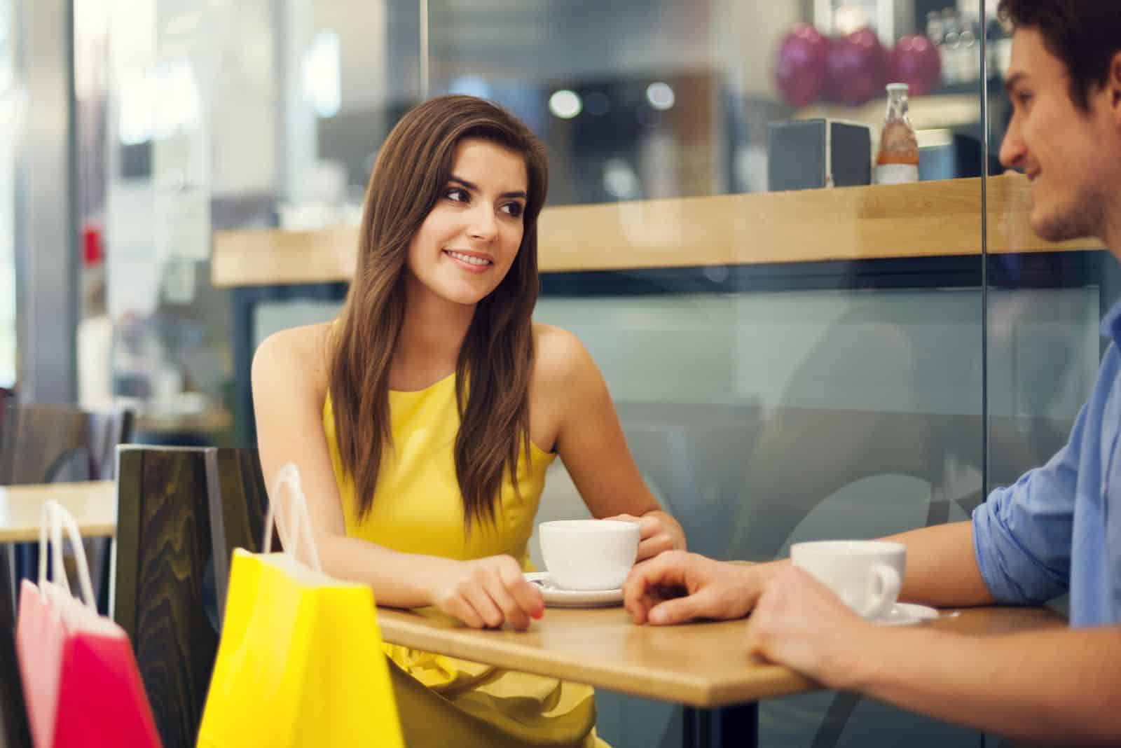 une belle fille est assise dans un café avec un homme et ils parlent