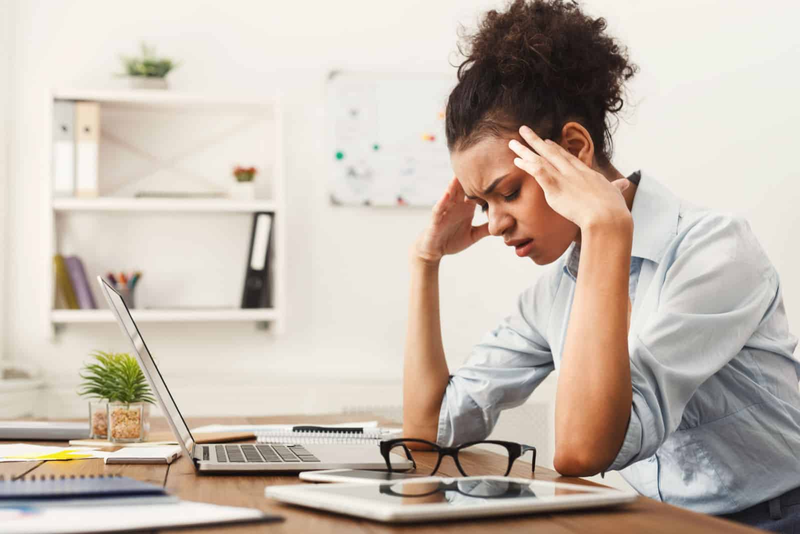 Femme d'affaires afro-américaine fatiguée avec mal de tête au bureau