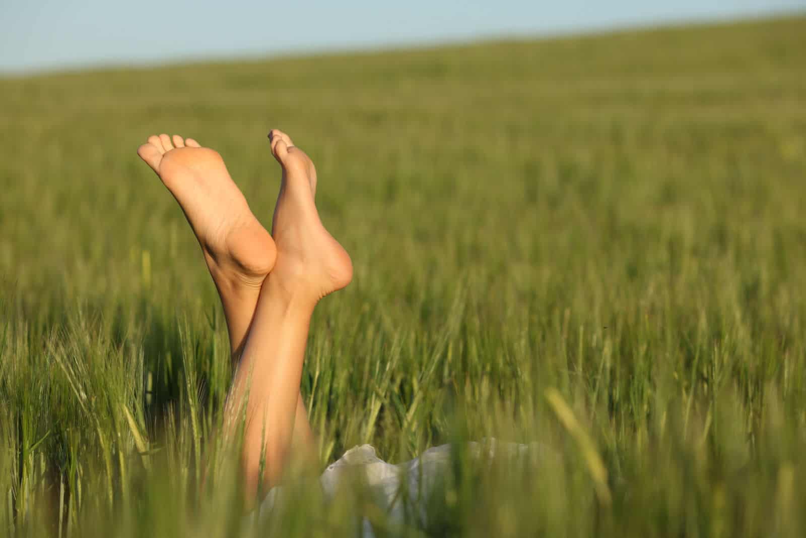 femme aux pieds nus se détendre les pieds dans un champ