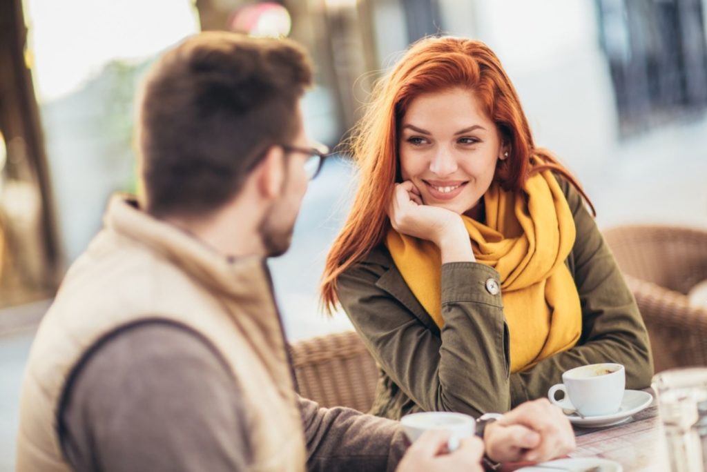 Séduisante jeune couple amoureux assis à la table du café à l'extérieur