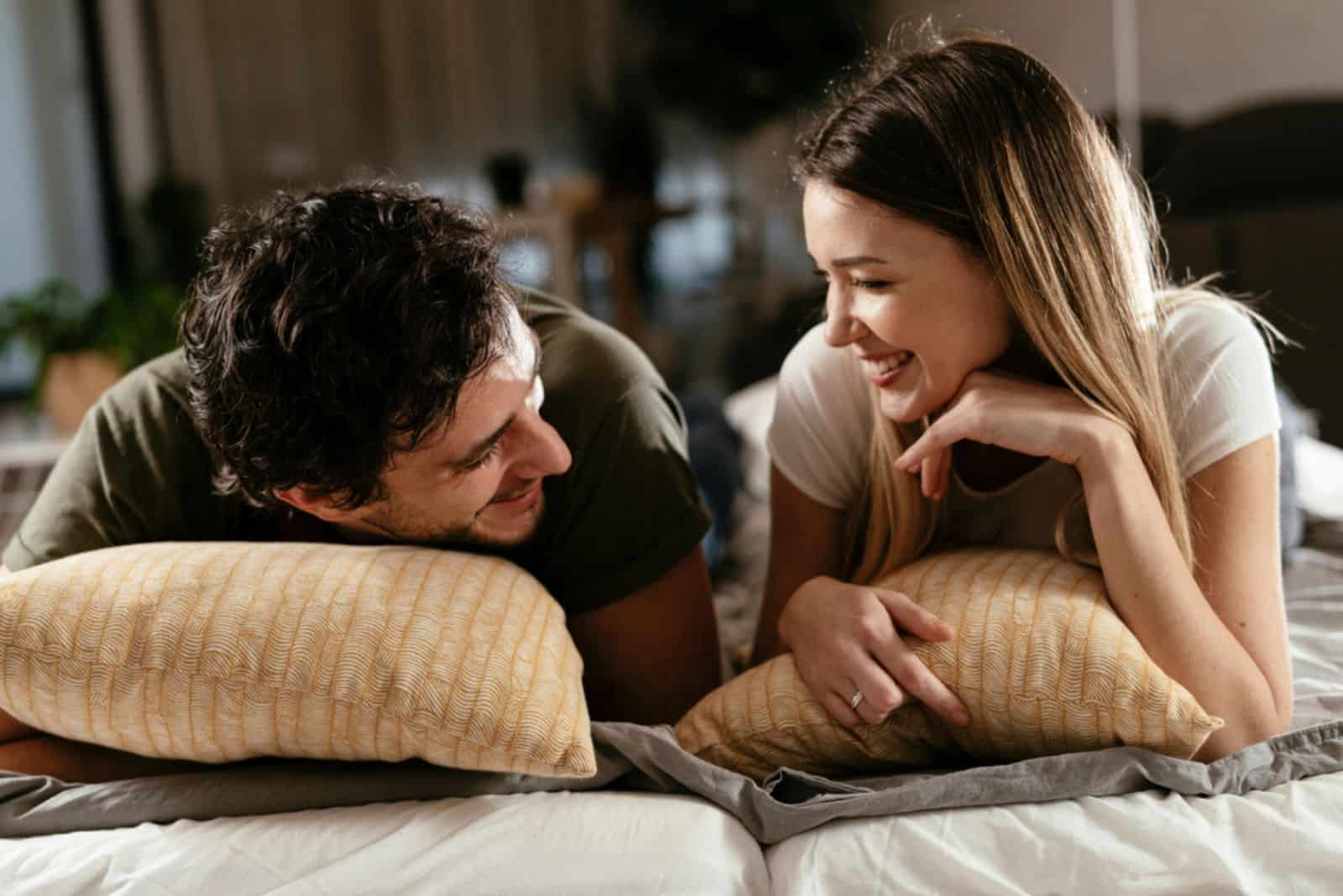 couple d'amoureux souriant allongé sur le lit et parlant