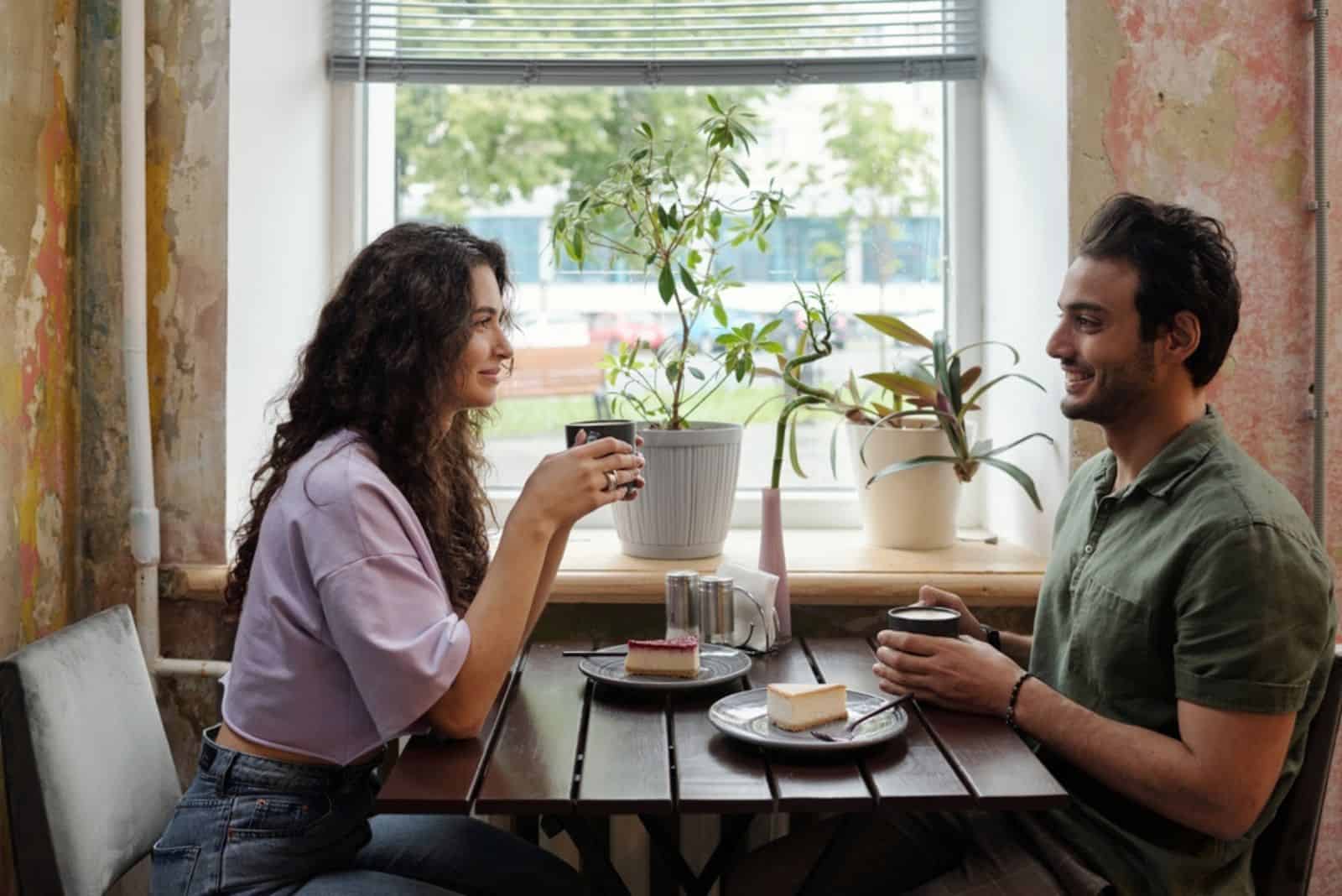 couple d'amoureux souriant assis dans un café prenant un café et parlant