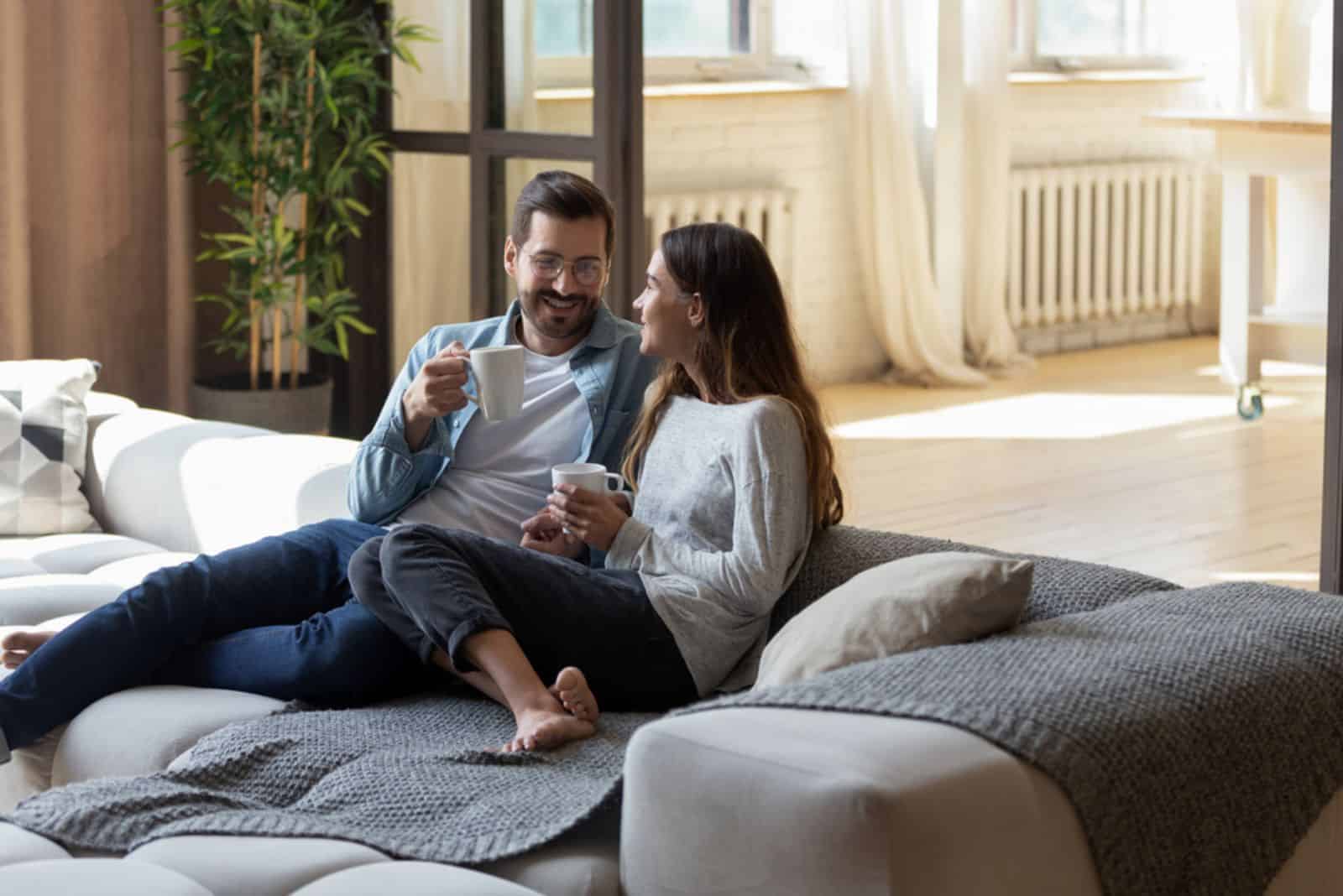 couple d'amoureux souriant assis sur un canapé et parlant