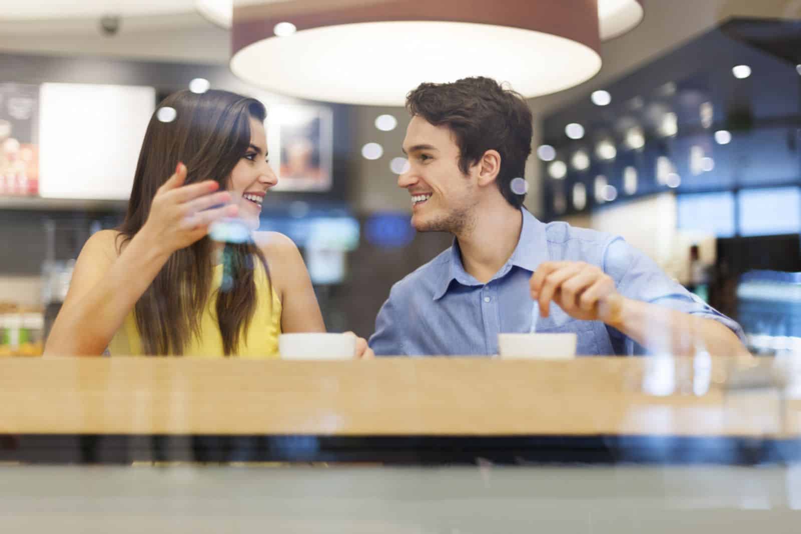 couple d'amoureux souriant buvant du café à une table dans un café
