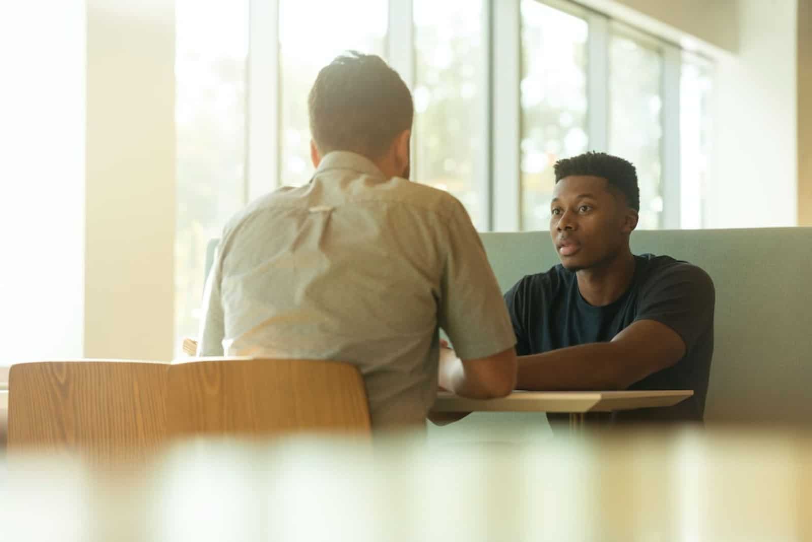 deux hommes sont assis à une table et discutent