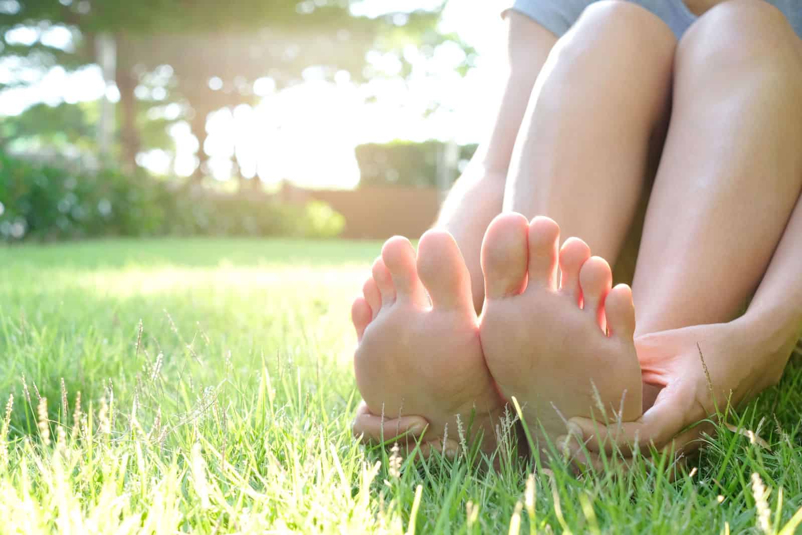 femme assise sur l'herbe Sa main prise au pied.