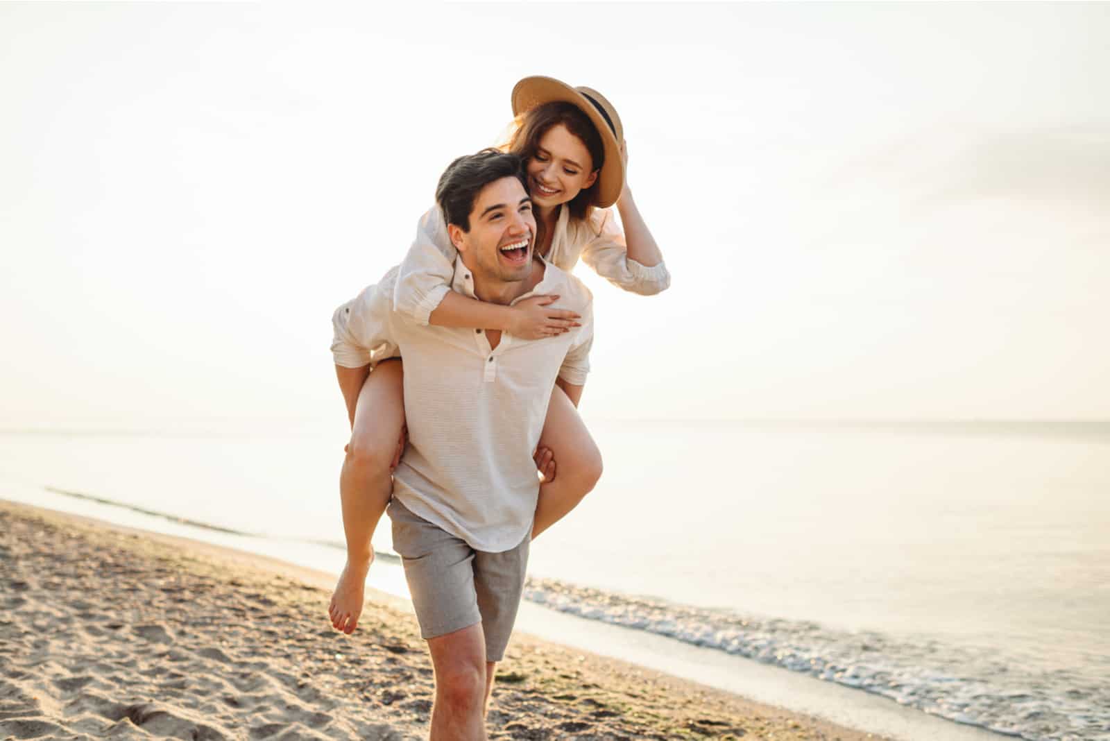 homme heureux portant sa petite amie sur le dos sur la plage