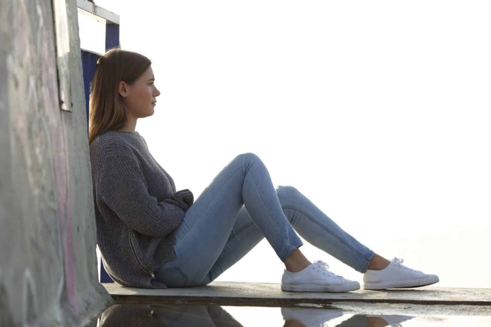 la fille est assise sur une plate-forme en bois et pense