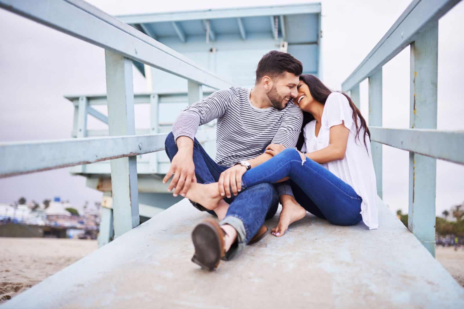 un couple d'amoureux est assis sur un pont en bois