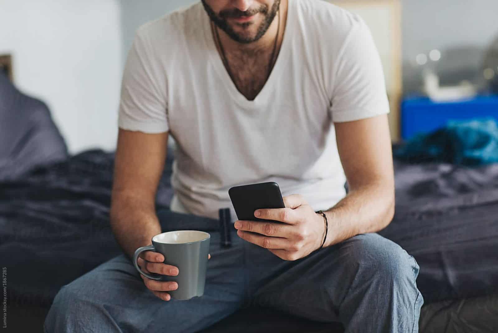 un homme est assis sur le canapé et tape au téléphone