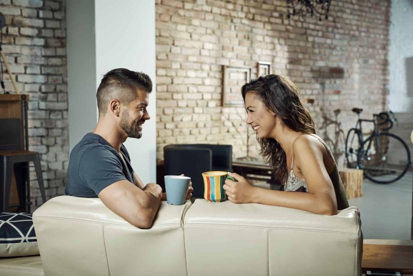 un homme et une femme sont assis sur le canapé et parlent autour d'un café