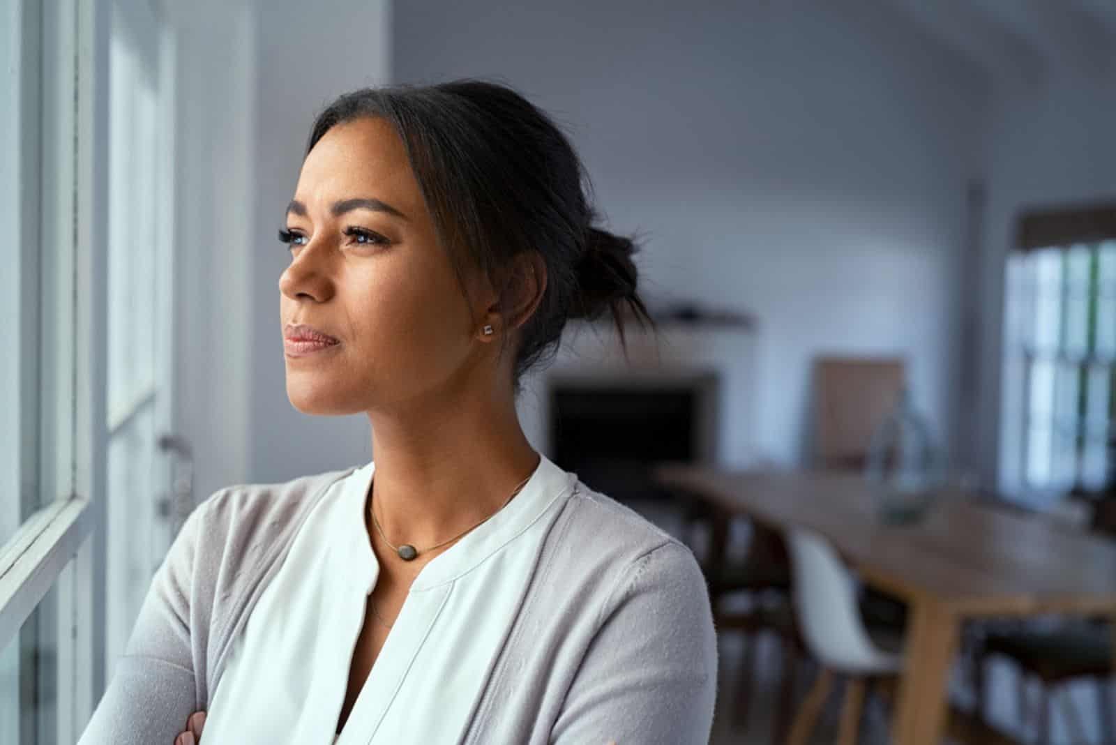 une femme imaginaire aux cheveux attachés se tient près de la fenêtre