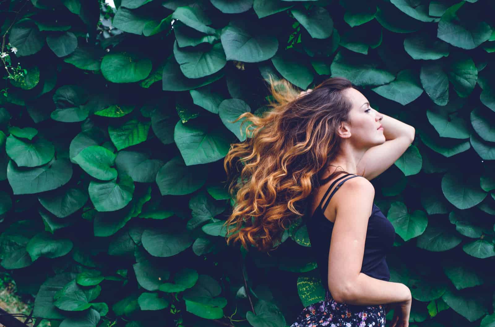 Femme photographiée dans la nature devant des feuilles vertes