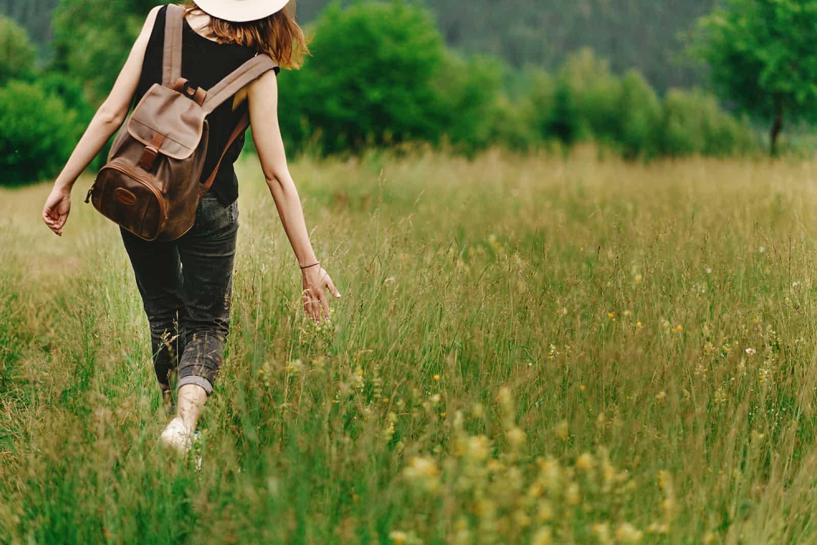 femme marchant dans le champ avec un sac à dos