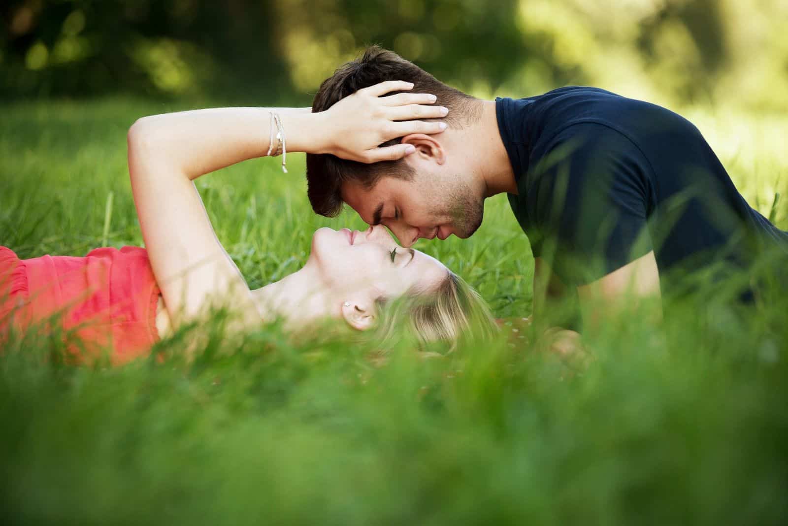 jeune couple câlins dans l'herbe verte