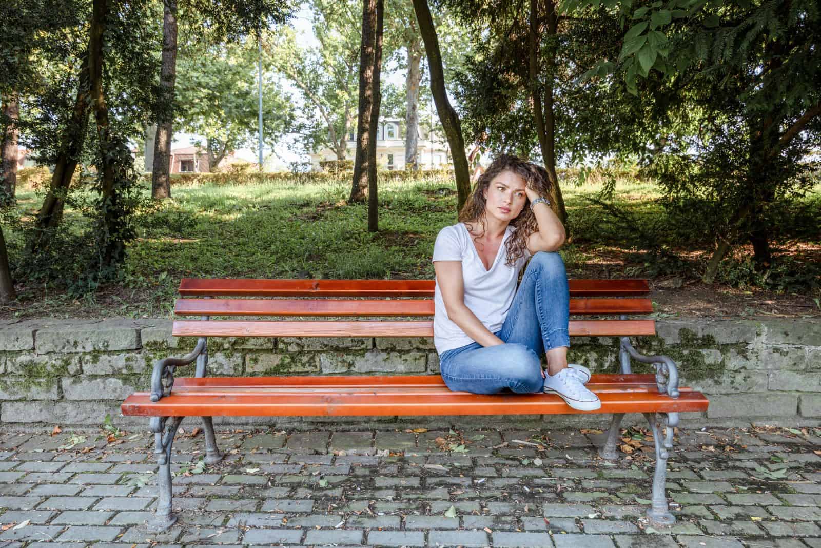 une fille solitaire est assise sur un banc de parc