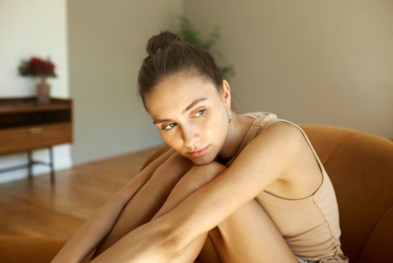 Superbe femme triste en vêtements de maison assis sur un canapé