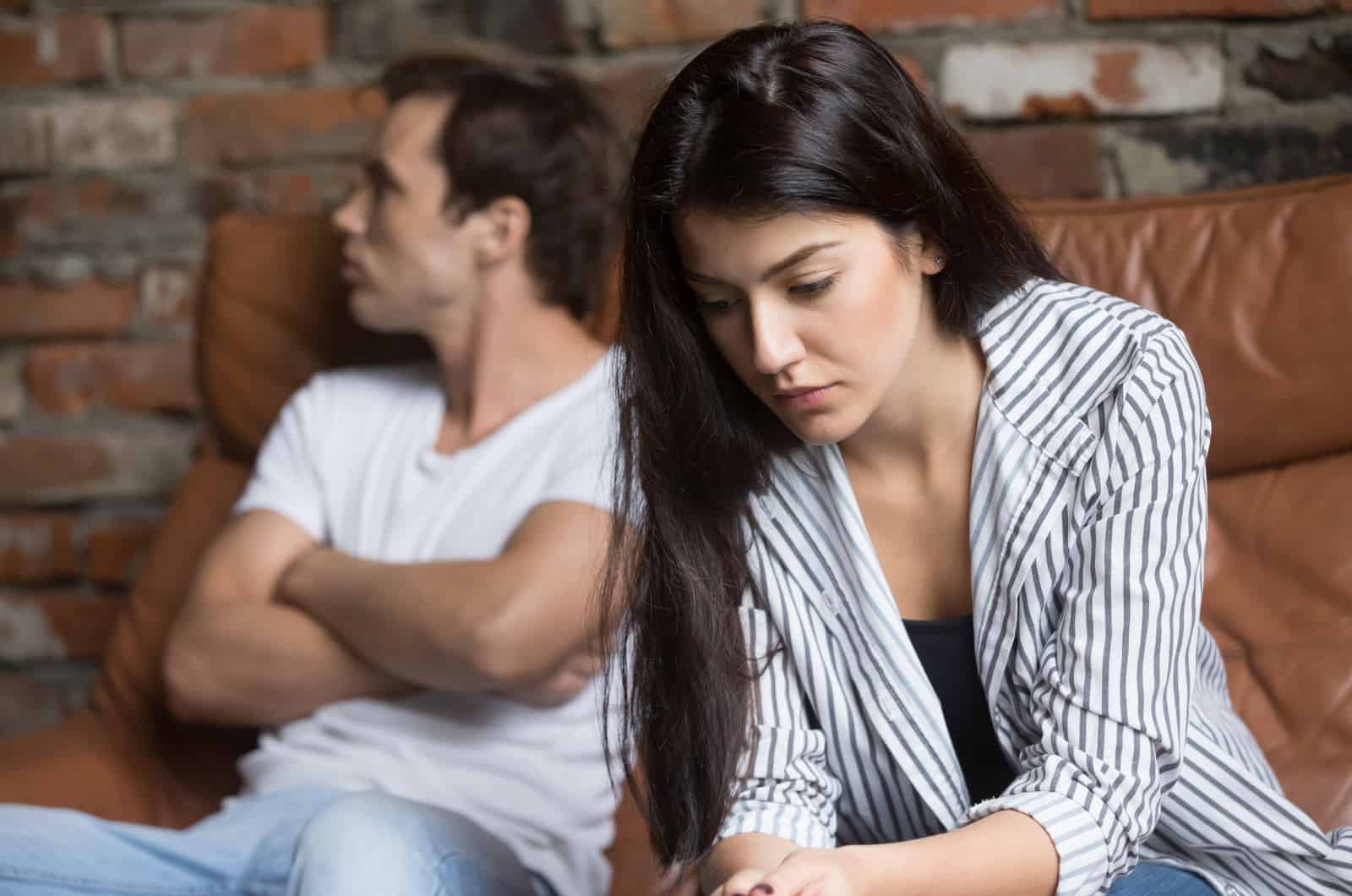 femme inquiète assise sur un canapé à côté de son petit ami