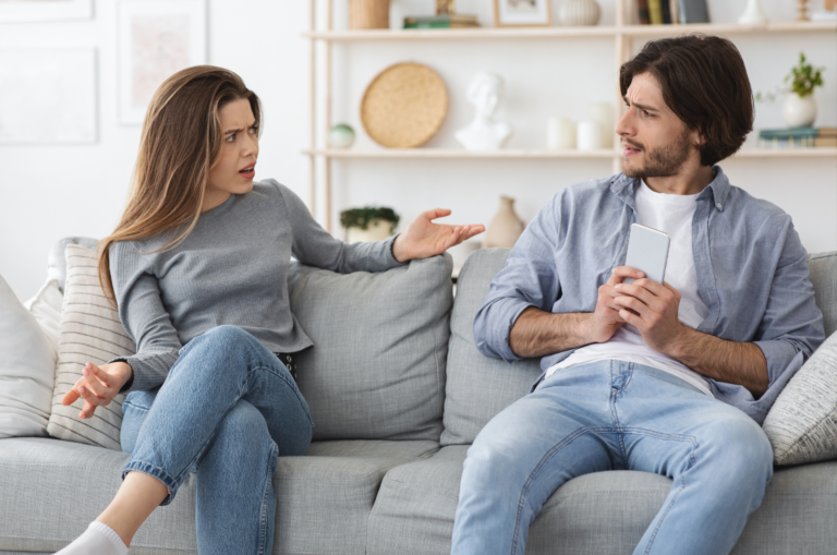 homme et femme assis sur un canapé pendant que l'homme cache son téléphone