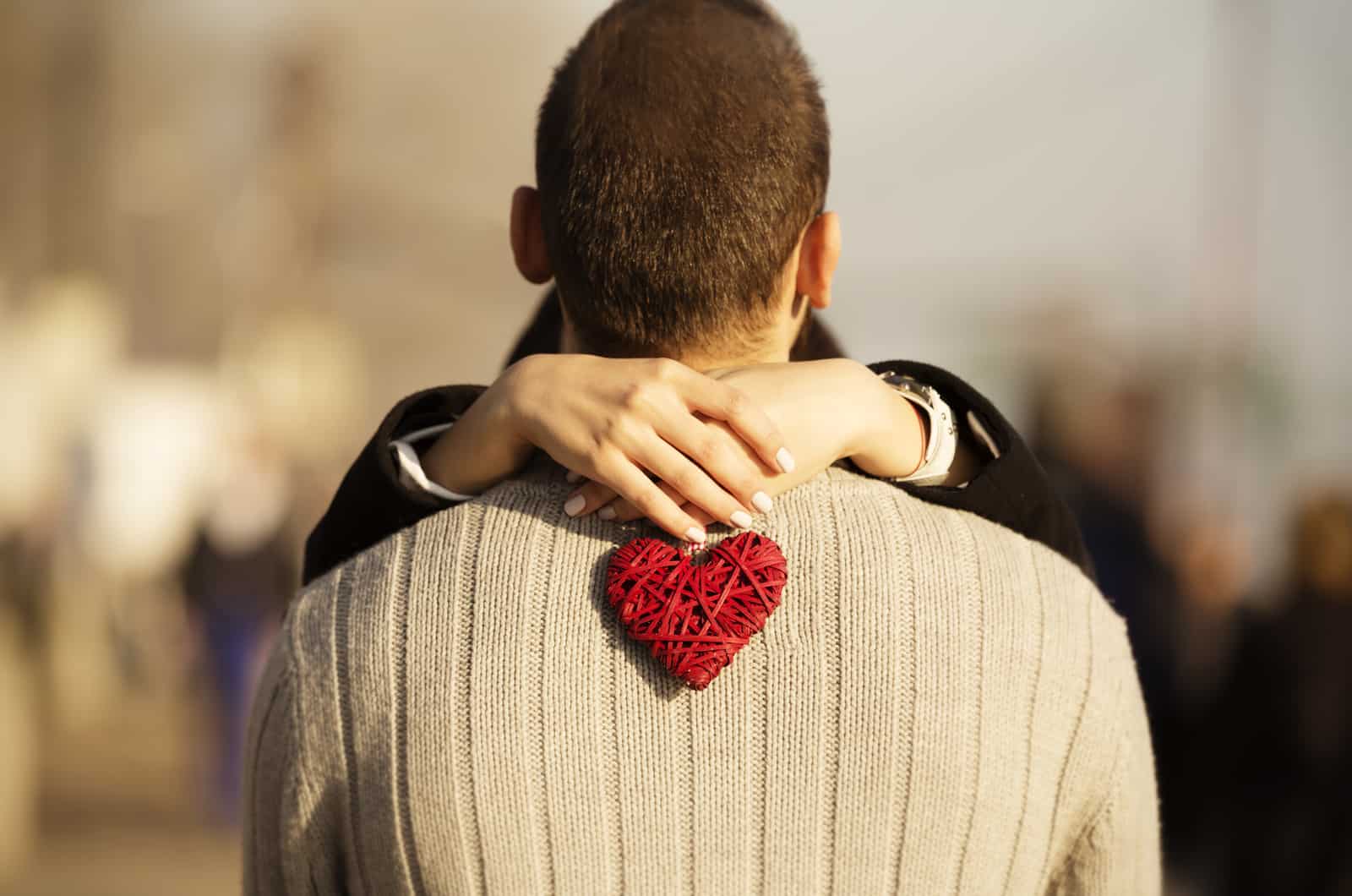 photo du dos d'un homme et des mains d'une femme tenant un petit coeur