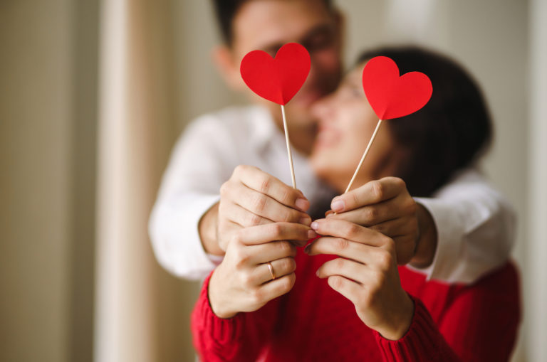 couple heureux tenant deux coeurs en papier sur un bâton
