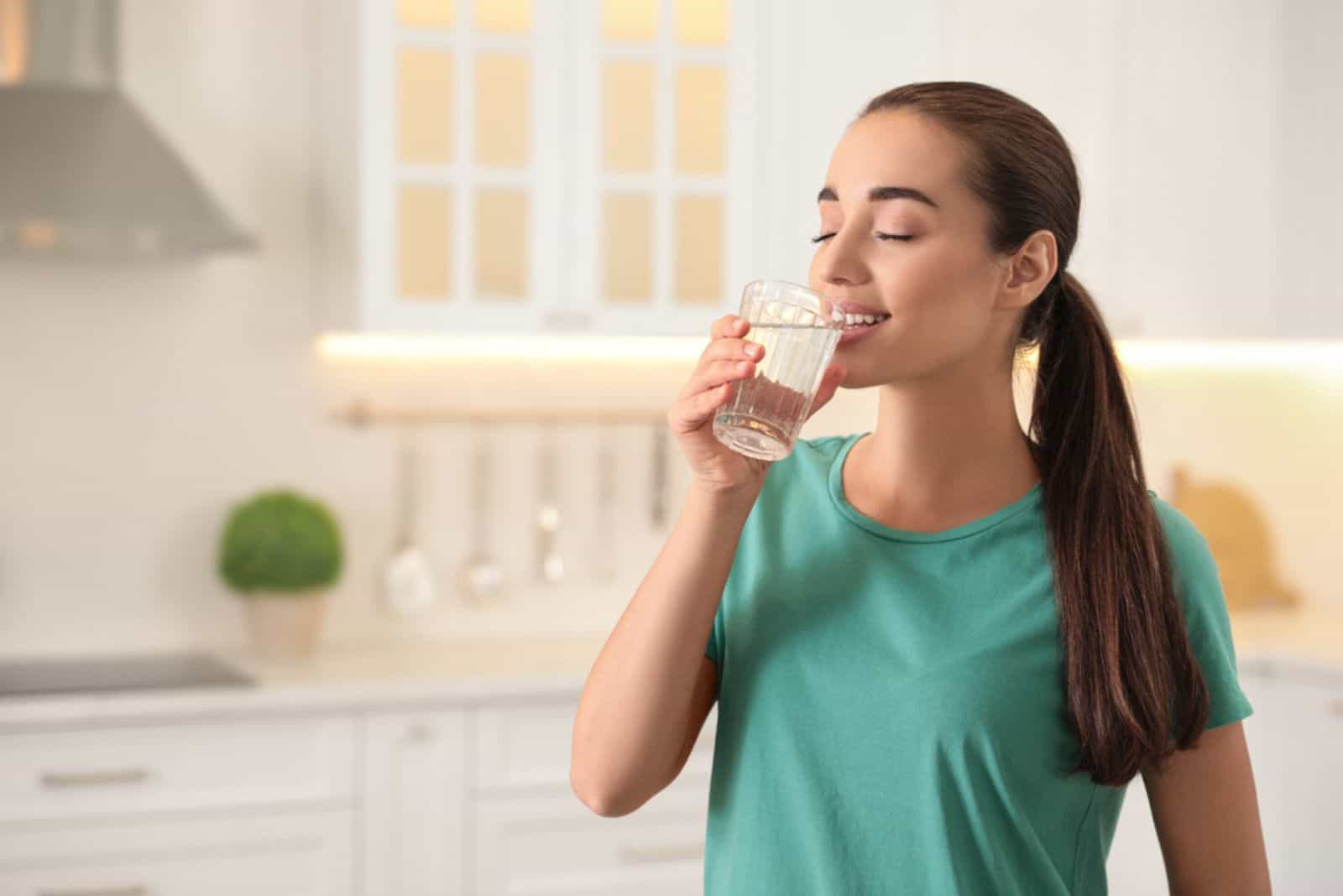 Jeune femme buvant de l'eau pure du verre