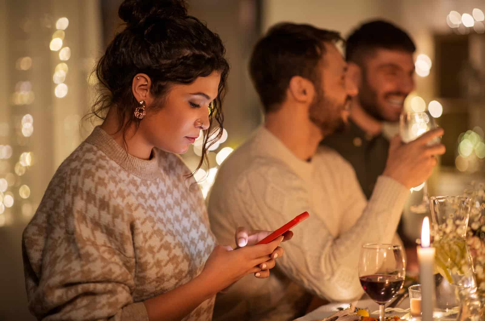 femme regardant son téléphone à table avec des amis