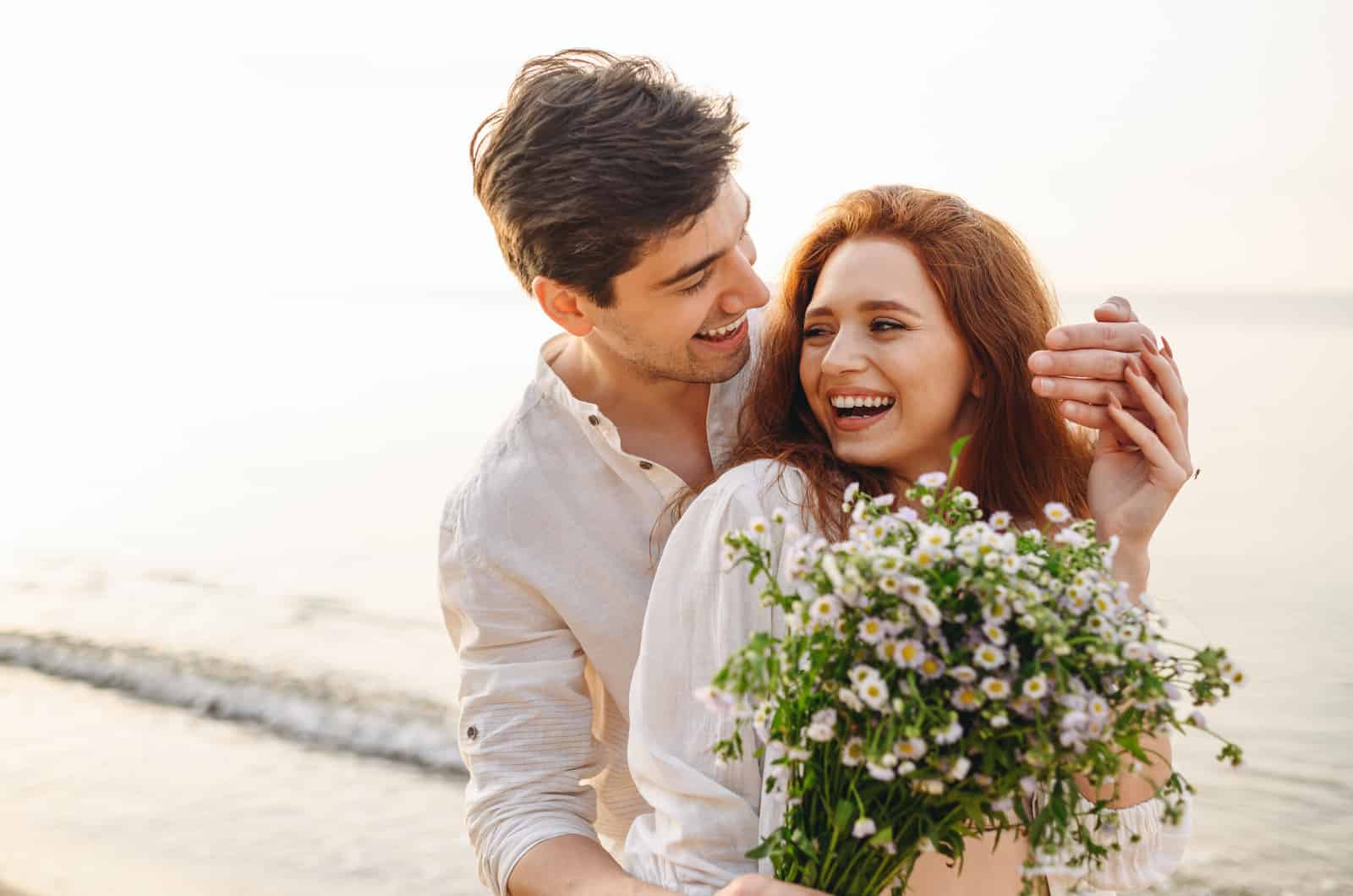 un homme surprend sa petite amie avec des fleurs à la plage