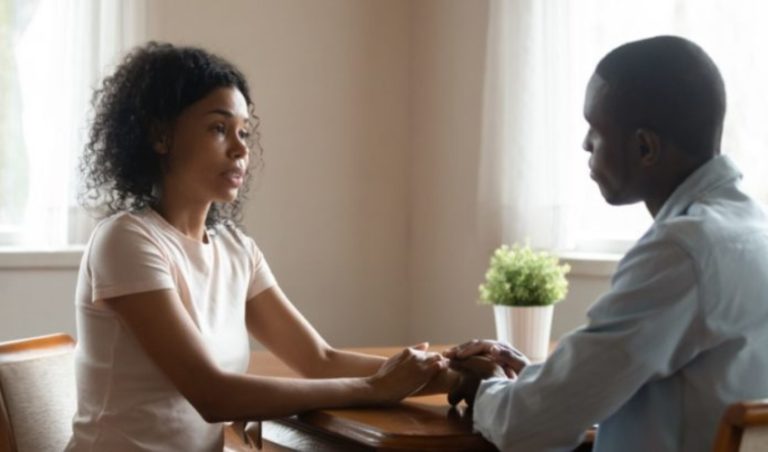 un homme et une femme sont assis a la table, se tiennent la main et parlent