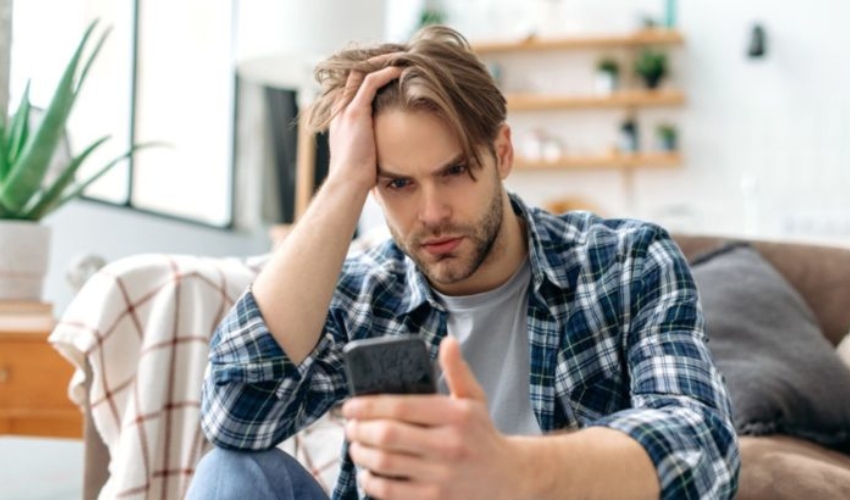 homme inquiet regardant un telephone portable