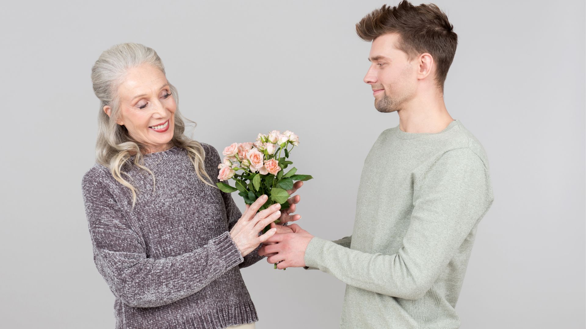 jeune homme donnant une bouquette de fleurs à une femme plus âgée