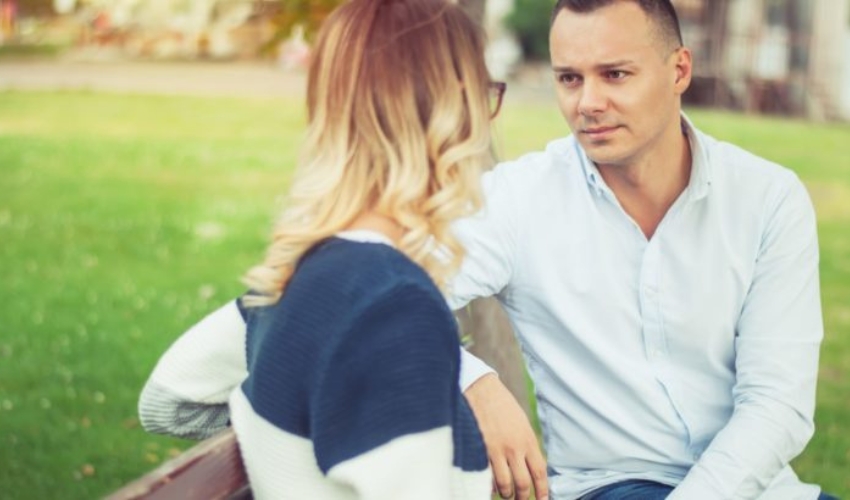 un homme est assis avec une fille sur un banc et ils parlent