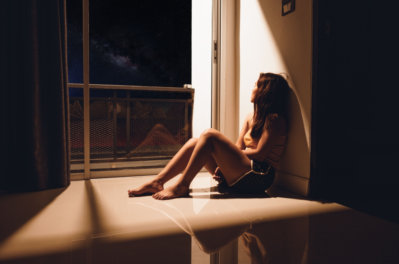 Jeune femme triste et déprimée assise sur le sol dans le salon regardant à l'extérieur