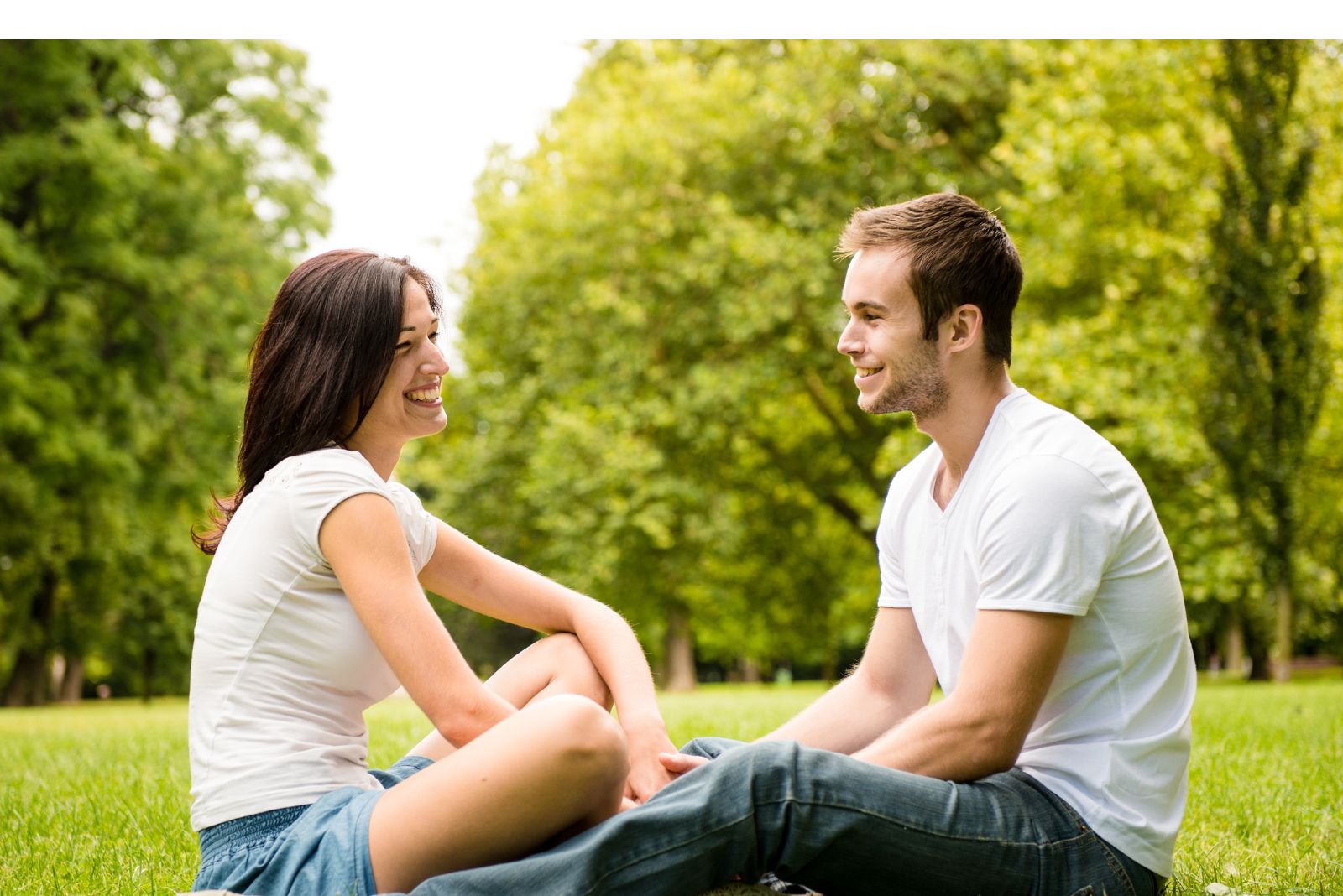 un couple amoureux est assis sur l'herbe l'un à côté de l'autre et parle