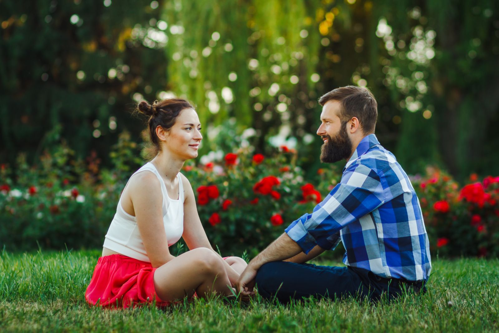 un homme et une femme s'assoient l'un à côté de l'autre sur l'herbe et parlent