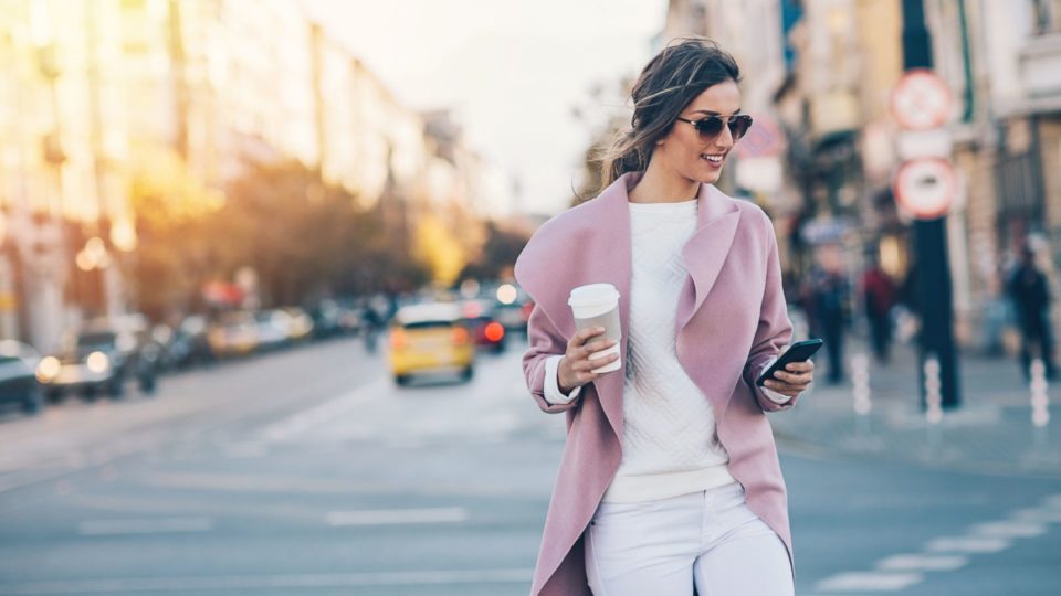 femme marchant dans la rue et souriant et tenant le telephone portable