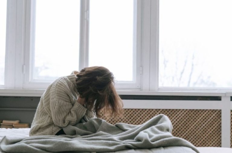 femme triste assise sur un lit