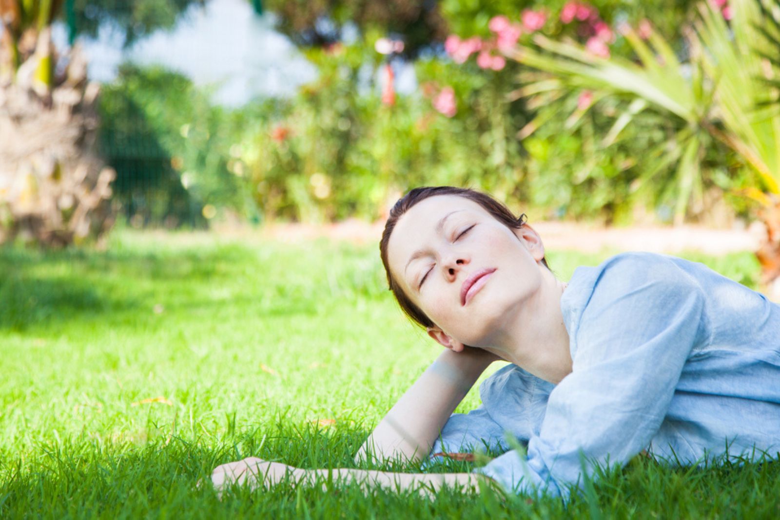 une femme aux yeux fermés aime s'allonger sur l'herbe