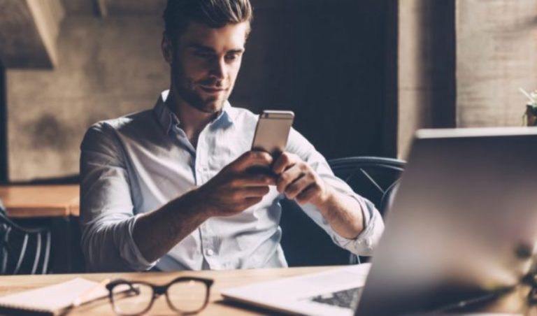 un homme est assis dans le bureau et les touches au telephone