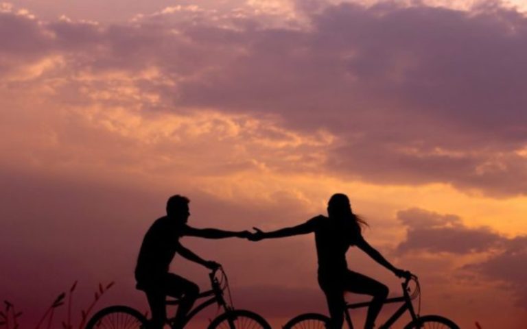 un homme et une femme font du velo et se tiennent la main